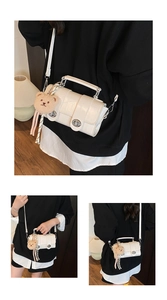 Detail of white crocodile embossed handbag with metal lock and cute bear charm