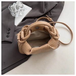 Detailed macro view of light brown pleated cloud handbag with magnetic closure and inner lining