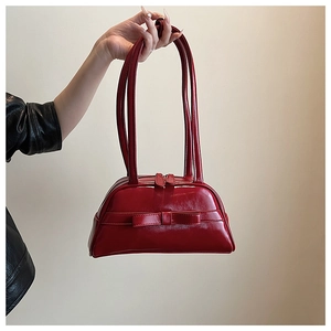 Detail of red glossy patent leather bowling bag with bow decoration and double zippers