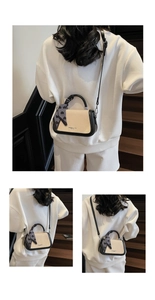 Detail of a chic cream straw handbag with black leather trim and decorative heart scarf