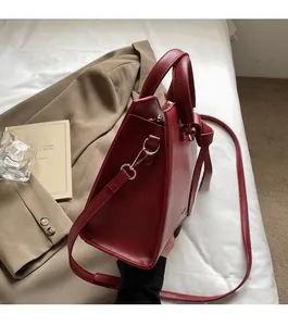 Détail du sac cabas en cuir rouge montrant le fermoir doré et le nœud latéral