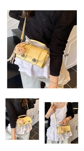 Detail of yellow crocodile pattern handbag with bear charm and silk ribbon on model