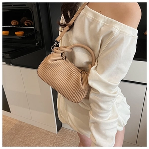 Detail of beige pleated handbag showing ruched texture and detachable shoulder strap