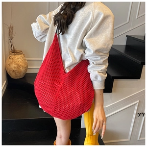 Red crochet knit hobo bag with large mesh texture shown in a minimalist indoor setting