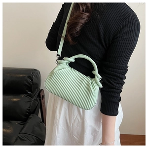 Close-up of mint green pleated handbag featuring twisted handles and PU leather texture