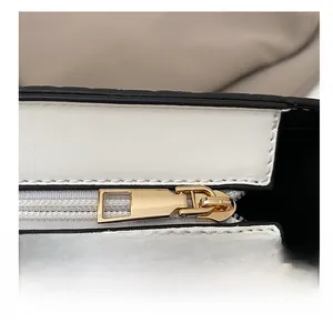 Macro detail of high-quality gold zipper hardware on a black and white leather bag