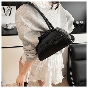 Close-up of stylish black patent leather bowling bag with glossy finish and top zipper