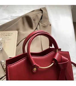 Détail du sac cabas bordeaux avec anneaux métalliques dorés et nœud en cuir chic