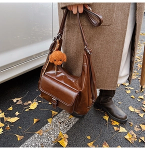 Detail of vintage brown oil wax leather shoulder bag with a cute poodle plush pendant