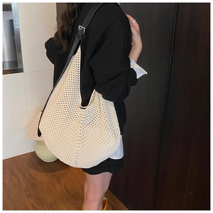 Detail view of woven straw shoulder bag with adjustable black leather strap for summer use