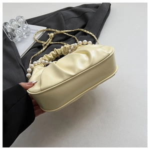 Detail of cream pleated cloud bag with white pearl handle and gold chain strap