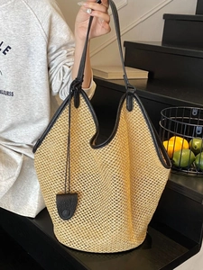 Handcrafted straw tote bag with black leather handles and large interior capacity