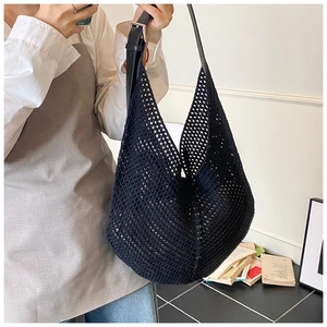Detail of black woven tote bag featuring mesh texture and adjustable leather shoulder strap