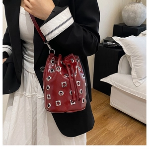 Detail of red drawstring bucket bag with shiny metallic eyelets and smooth leather texture