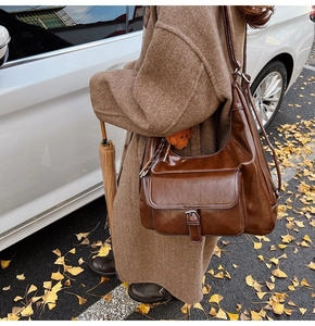 Brown oil wax leather tote bag worn by a model against a fall street background