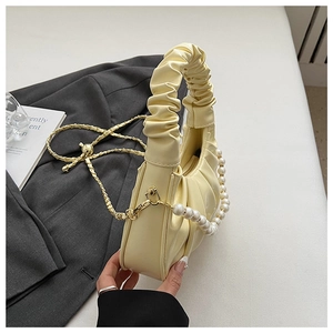 Detail of cream pleated cloud bag with elegant pearl chain and fine metal strap