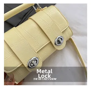 Detail of crocodile pattern texture and silver metal turn-locks on a yellow handbag