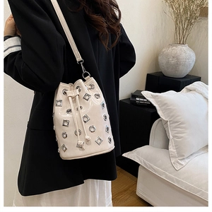 Detail of cream glossy leather bucket bag with silver metal eyelets and rivets