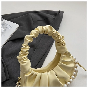 Detail of light yellow ruched cloud bag featuring decorative pearl chain and ruffled handle