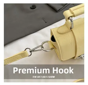 Detail of high-quality silver metal hook on yellow faux crocodile skin handbag