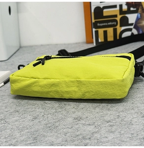 Detail of neon green nylon bag showing wrinkled texture and dual black zippers
