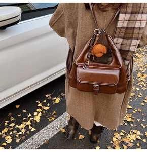 Detail of dark brown oil wax leather shoulder bag with a cute teddy bear plush charm