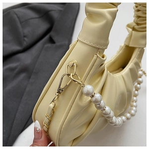 Close-up of cream pleated dumpling bag with pearl metal chain and golden hardware
