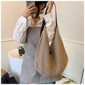 Close-up of beige woven texture and black leather shoulder strap of this tote bag