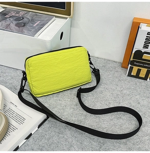 Detail of neon green nylon crossbody bag with adjustable strap on a minimalist lifestyle setting