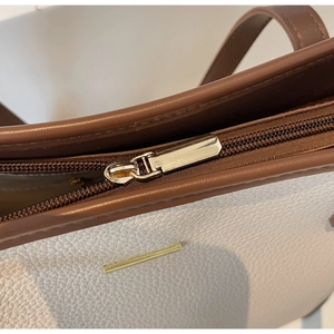 Dettaglio della borsa tote in pelle martellata con finiture dorate e cerniera metallica