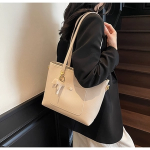 Close-up of beige faux leather tote bag with lychee texture and elephant charm