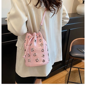 Detailed view of pink metallic bucket bag with silver grommets worn by a model in white suit