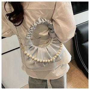 Detail view of light blue pleated dumpling bag with scrunchie handle and pearl chain