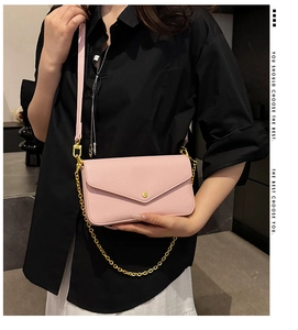 Close-up of pink envelope bag with lychee grain leather, gold buckle, and chain strap