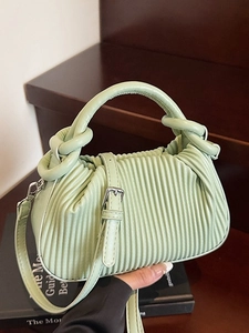 Chic light green ruched handbag with twisted handle and metal buckle on bookshelf
