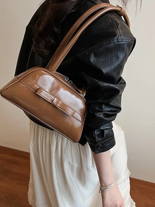 Glossy brown bowling handbag with a leather bow detail and long handles for women