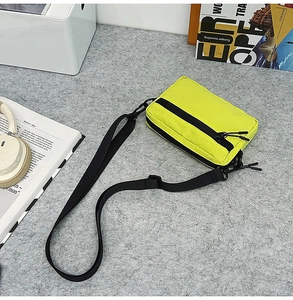 Detailed top view of a lime green nylon crossbody bag with black zipper and straps