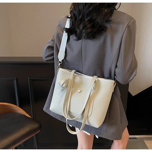 Detail of grey lychee leather tote bag with elephant charm on stylish business suit