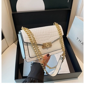 Detail of white crocodile pattern shoulder bag with golden chain and envelope buckle