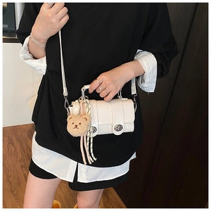 Detail of white crocodile pattern square bag with plush bear charm and silk ribbon