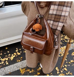 Close-up of vintage brown leather backpack with teddy charm and buckle detail