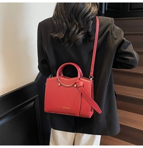 Modèle portant un sac à main rouge avec détails noués et boucles dorées chic
