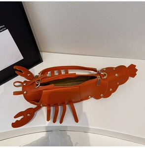 Detail view of the orange lobster-shaped crossbody bag with gold metal zipper and rivets