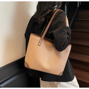 Dettaglio della borsa tote in pelle beige con bordi marroni e finiture metalliche dorate
