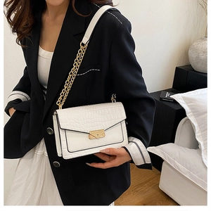Detail of white crocodile pattern shoulder bag with golden chain and metal buckle