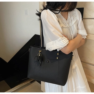 Detail of black lychee grain leather tote bag featuring a cute elephant charm