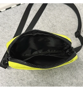 Internal view of neon yellow nylon crossbody bag featuring black lining and inner pocket