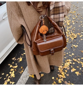 Brown oil wax leather hobo bag with a plush puppy charm and front flap pocket detail