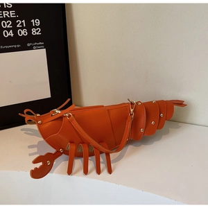 Detail of vibrant orange lobster-shaped creative bag with gold studs and metal zipper