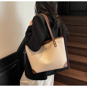 Dettaglio della borsa tote crema e marrone con trama grana e logo metallico minimal